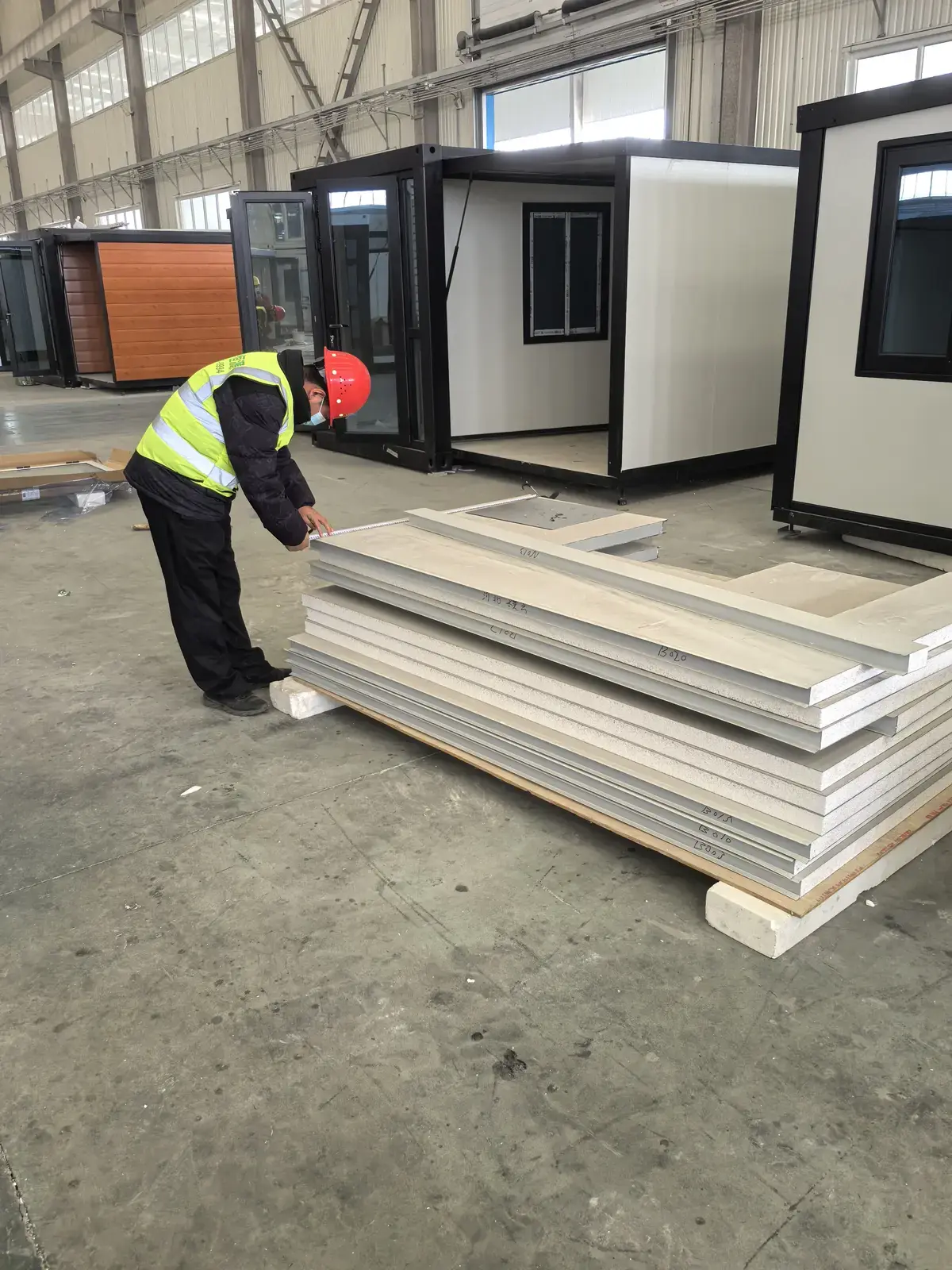 Factory worker positioning a building panel during modular production