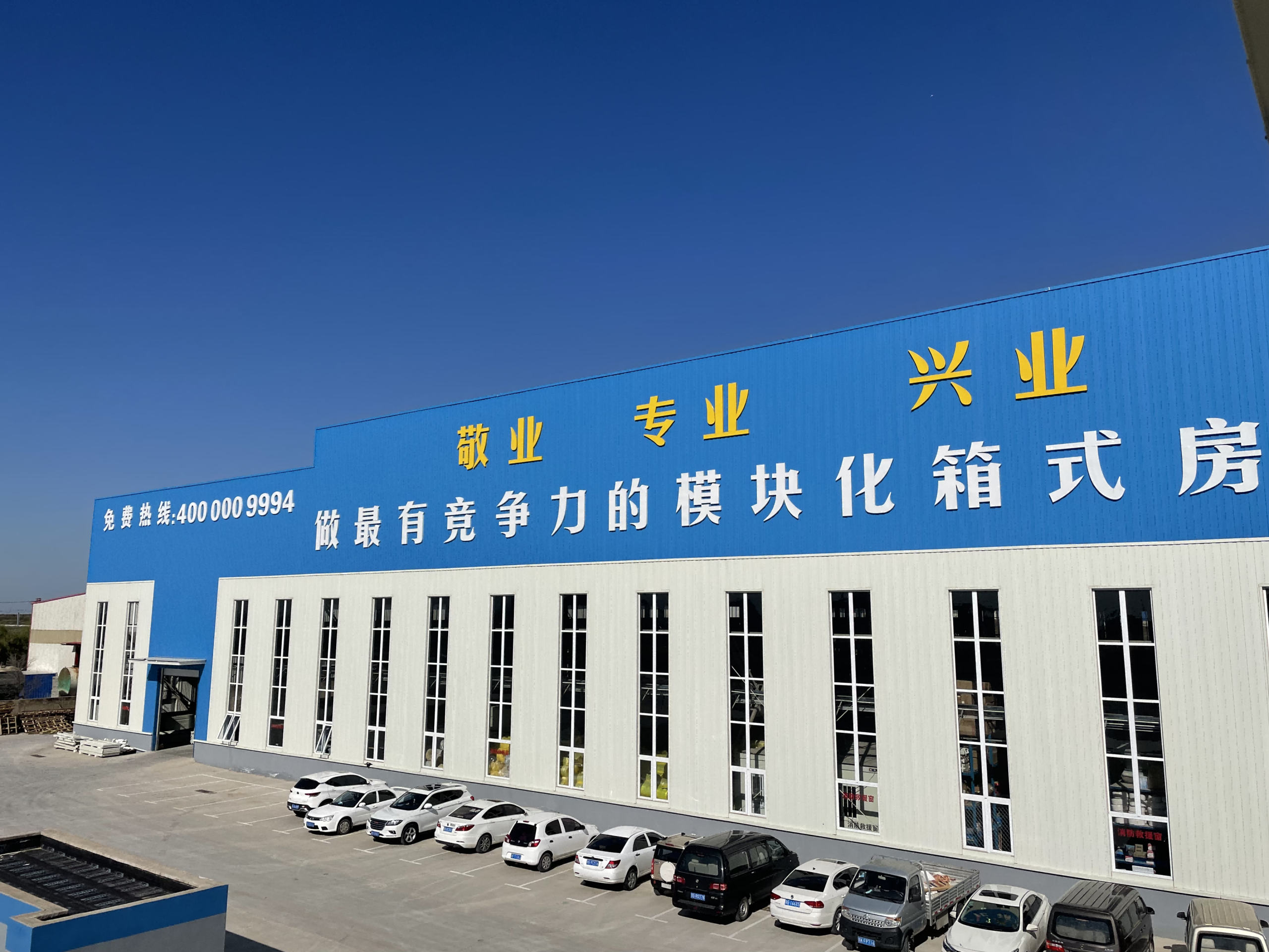 Front view of the MZ ECO container house factory with tall windows along the production hall