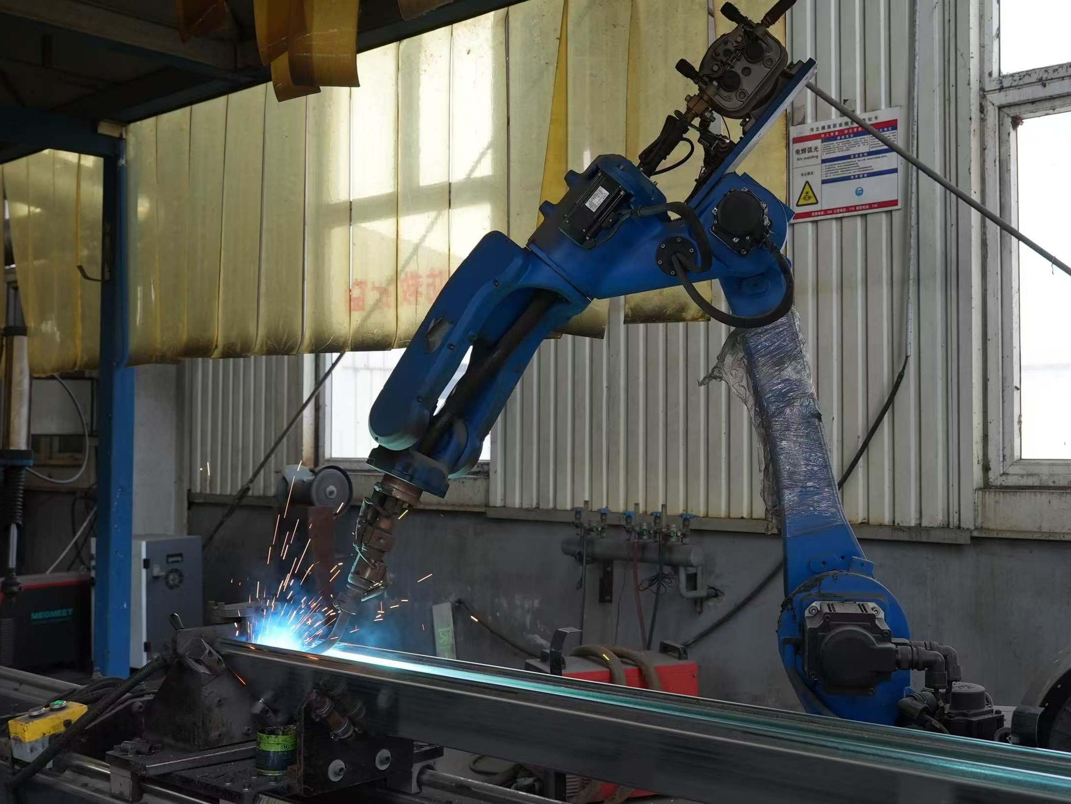 Industrial robotic arm welding a steel frame at MZ ECO modular house factory