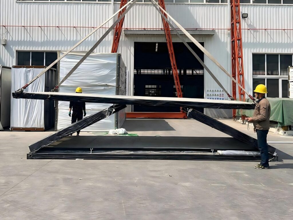 Folding container house unfolded in the factory yard, black steel frame with the roof panel lifted by crane slings