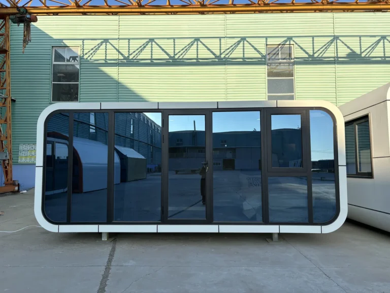 A30 white apple cabin with black-framed panoramic glazing in the factory yard