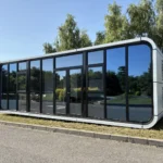 White panoramic apple cabin installed beside trees in a park