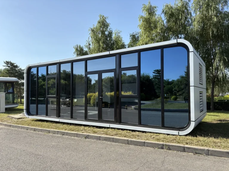 White panoramic apple cabin installed beside trees in a park