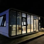 Park apple cabin illuminated at night with its interior visible through the glass front
