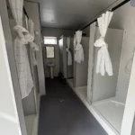 Shower facilities apple cabin interior with a corridor and curtained shower compartments
