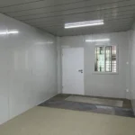 View toward the entrance inside the cream-panel detachable container house before final floor finishing