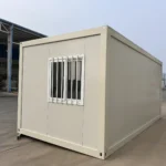 Opposite end of the white detachable container house showing a barred window
