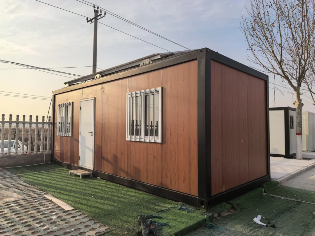 Wood-look detachable cabin with a dark frame and an entrance between two barred windows