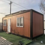 Wood-look detachable cabin with a dark frame and an entrance between two barred windows