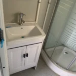 Bathroom vanity and enclosed shower inside the wood-look detachable cabin