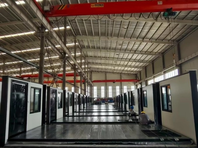 Rows of MZ ECO container house modules with window openings lined up in the assembly hall