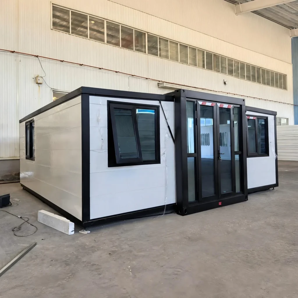 White expandable container house with black framing, a glazed entrance and awning windows inside the factory