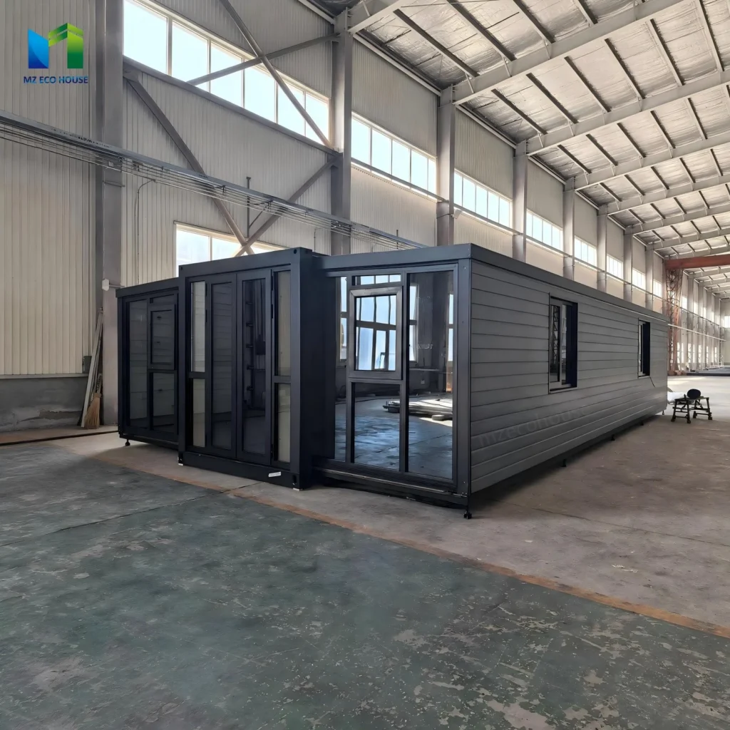 Grey expandable container house with a glazed front and horizontal side panels inside a factory