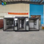 Grey glazed-front expandable container house during assembly with its wing panels open