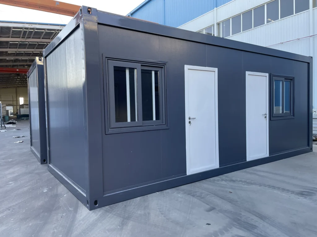 Grey flat pack container cabin with two entrance doors and barred windows