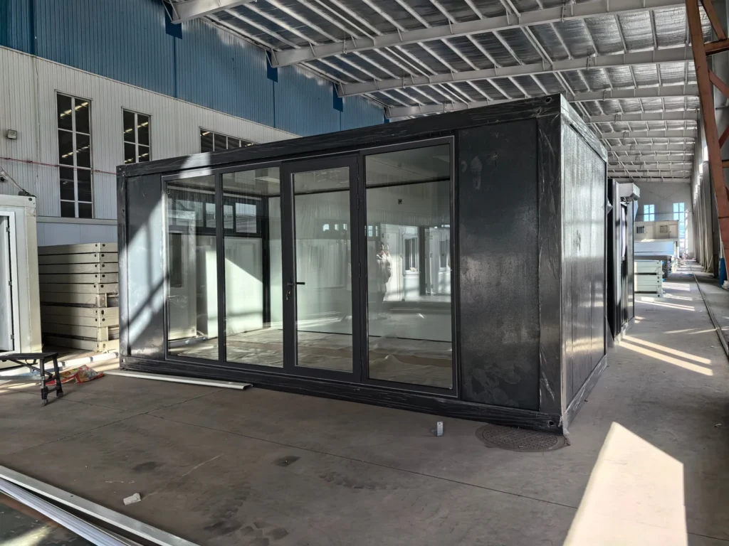 Dark-framed flat pack container office with full-height glazing