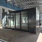 Dark-framed flat pack container office with full-height glazing