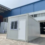 Standard flat pack container house with light-coloured panels and an entrance door