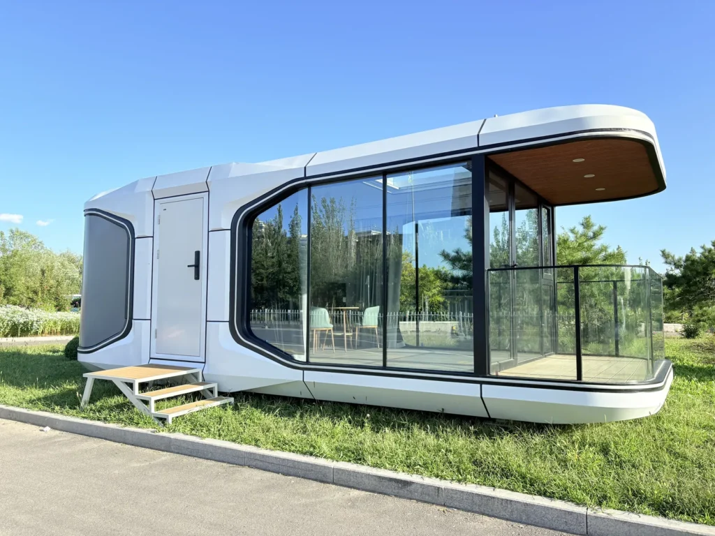 White space capsule house with panoramic glazing and a covered balcony beside a lawn