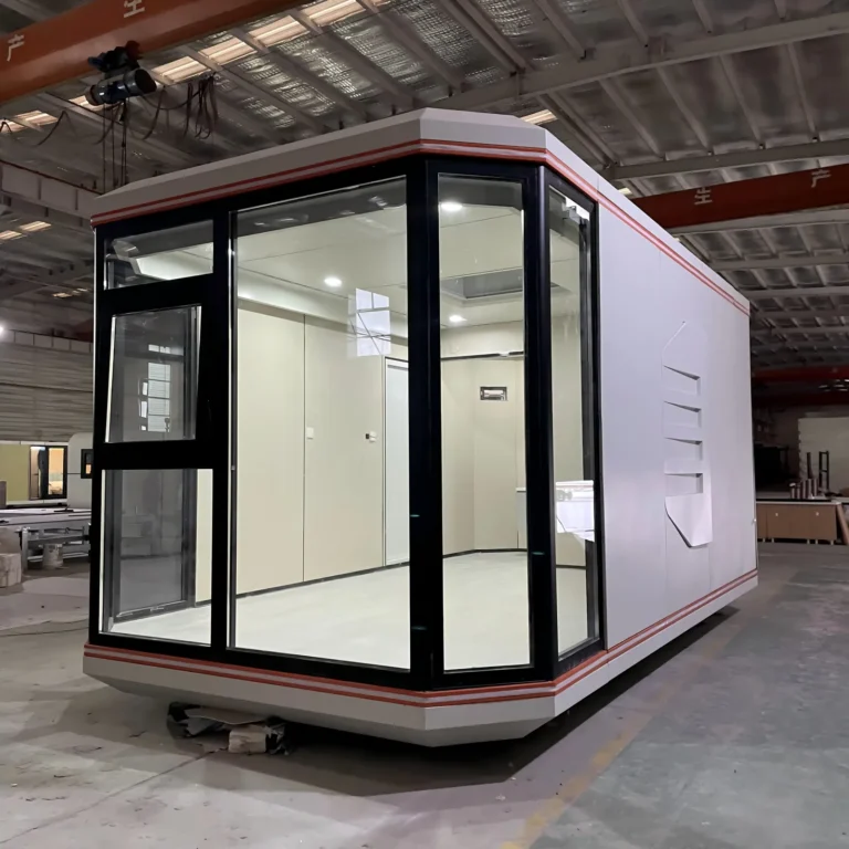 Compact assembled capsule with light wall panels and dark corner glazing inside the factory