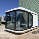 White E30 space capsule house with dark panoramic corner glazing in the outdoor display area