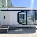 Side entrance and dark-framed glazing on the white E30 space capsule house
