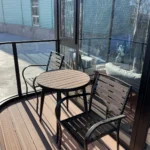 Table and chairs on the covered G70 balcony beside the glazed bedroom