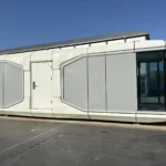 Long white and grey two-room capsule reference with a central side entrance and dark panoramic glazing