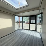 Unfurnished capsule room with panoramic corner glazing, wood-look flooring and a skylight