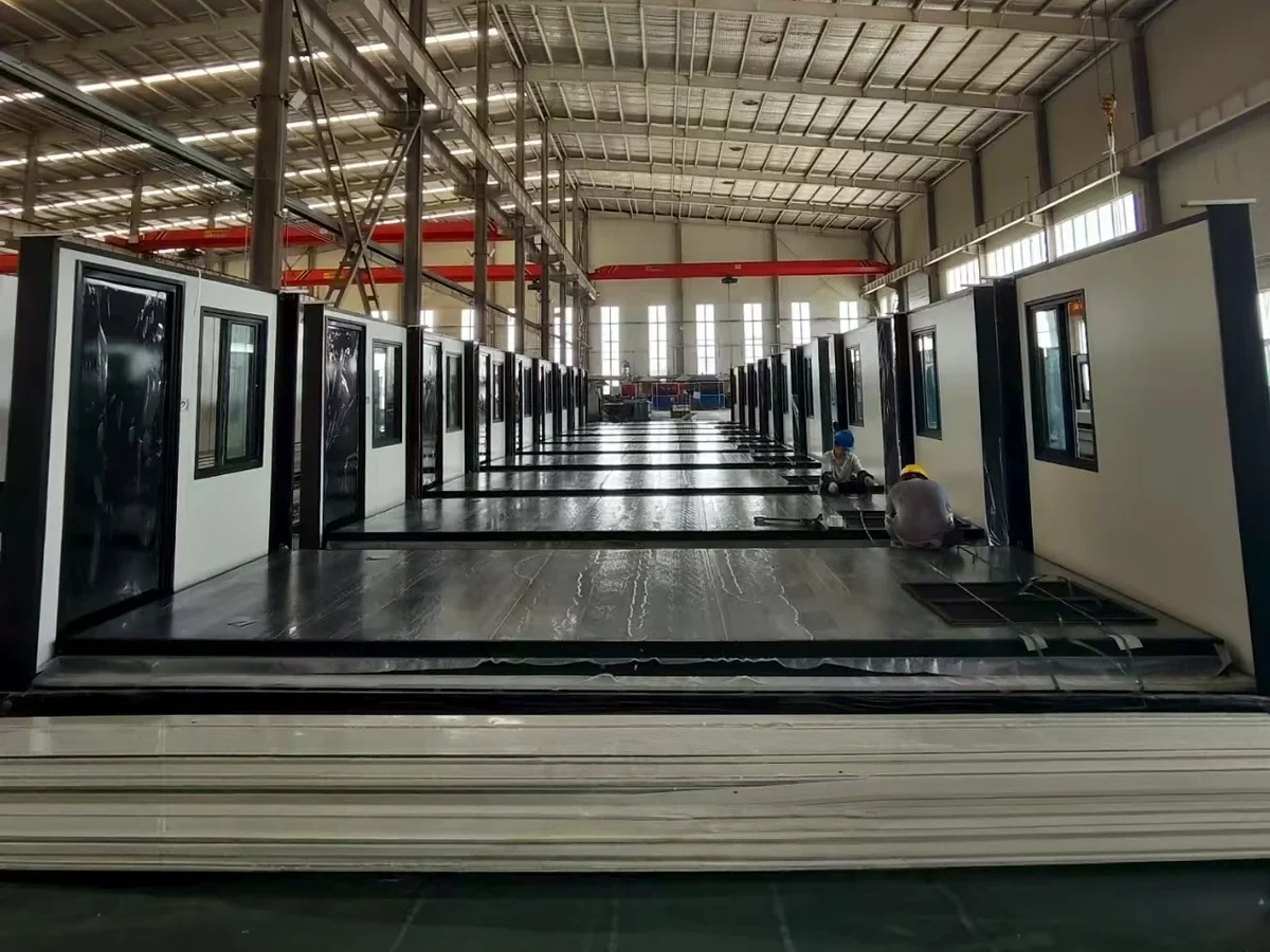 Container house manufacturing line beneath a red overhead crane