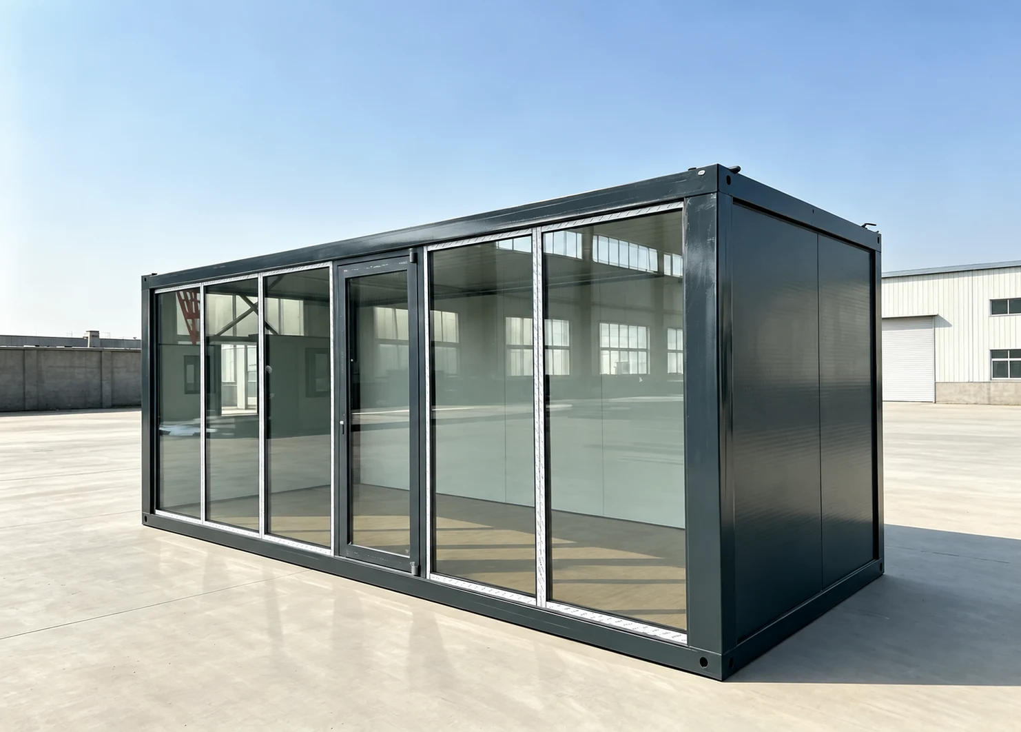 Dark-framed flat pack container house with full-height glazed walls