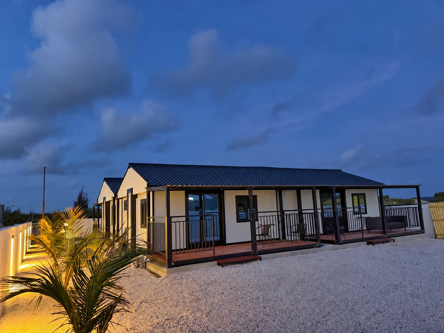 A modular home and illuminated garden at dusk