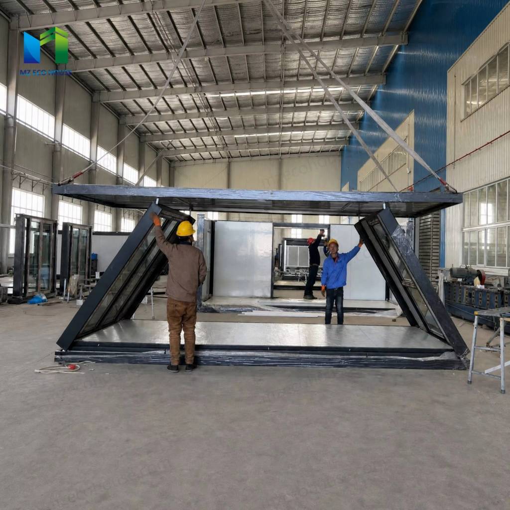 Workers beside a Z-type folding container house inside a factory workshop.