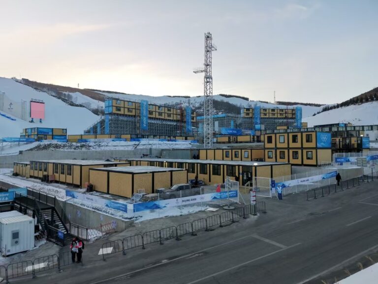Gold modular container camp buildings installed on a snow-covered construction site with scaffolding in winter