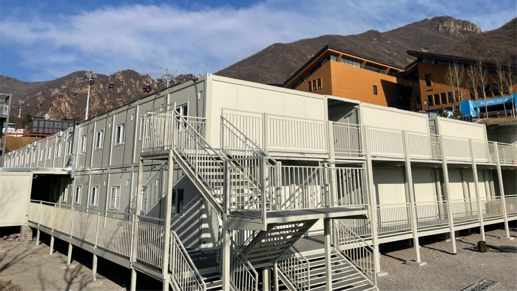 Two-storey prefab accommodation building with external staircase and walkway railings on a mountain site