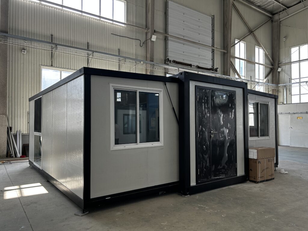 40ft butterfly expandable container house with a black steel frame and white insulated walls, assembled on the factory floor before delivery