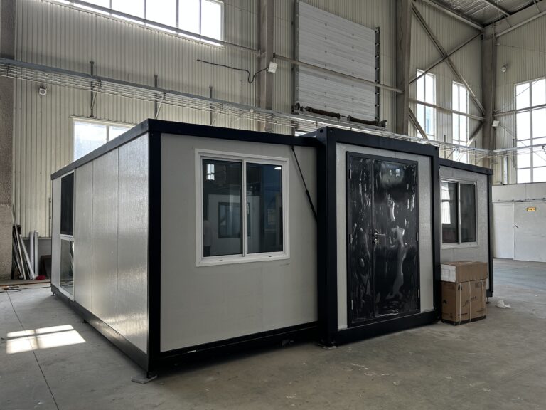 40ft butterfly expandable container house with a black steel frame and white insulated walls, assembled on the factory floor before delivery