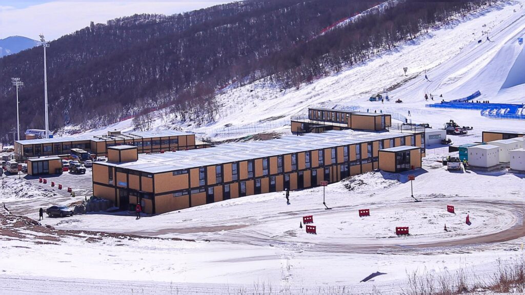 Remote site container camp of linked gold modular units in a snowy valley below snow covered mountain peaks